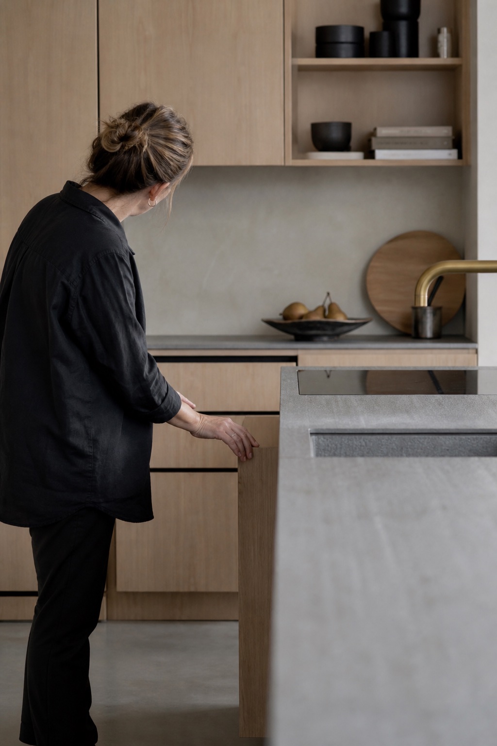 Une cuisiniste vérifie les tiroirs d’une cuisine contemporaine en bois clair